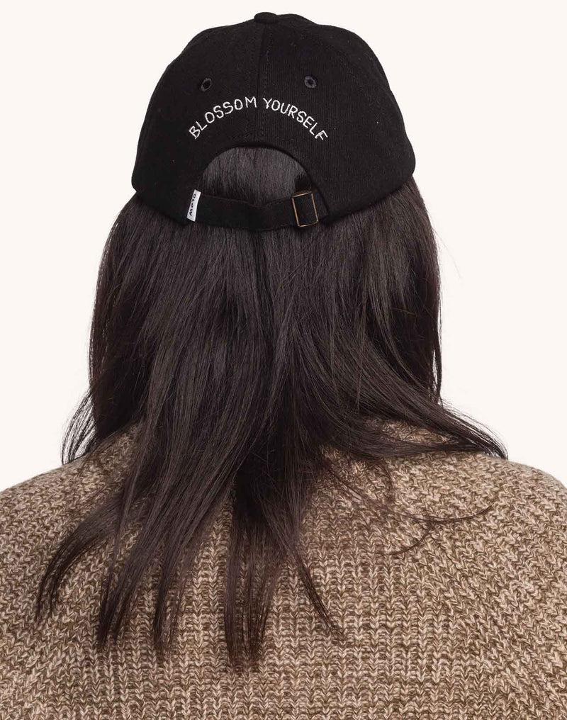Schwarze OLOW Blossom Yourself Cap am Model mit rückseitigem Schriftzug